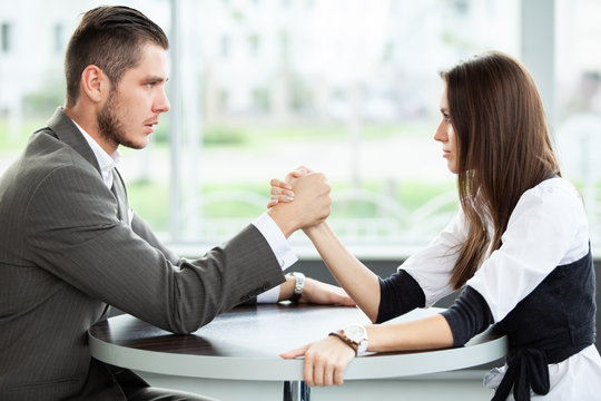 business and office concept - businesswoman and businessman arm wrestling during meeting in office.