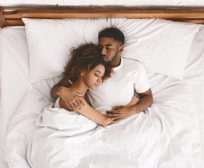 Young black couple sleeping together in bed