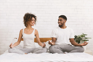 Young black family meditating in bed together