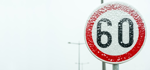 Traffic road speed limit 60 sign on the street covered with snow in danger slippery winter season...