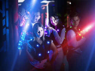 Young people with laser pistols in bright beams