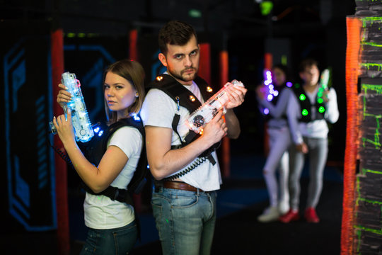 Man and woman standing back to back with laser pistols