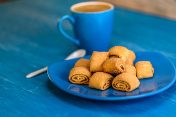 Cookies rolls with jam on a wooden turquoise background.