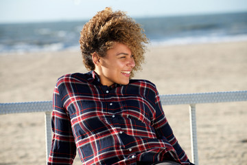 happy young african american woman sitting at beach