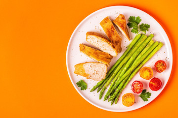 Roasted chicken breast with asparagus and tomatoes.
