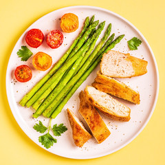Roasted chicken breast with asparagus and tomatoes.