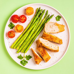 Roasted chicken breast with asparagus and tomatoes.