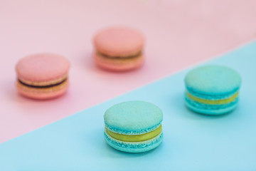 Sweet colorful French macaroon biscuits on pink and blue pastel background, top view. Flay lay selection of macarons.