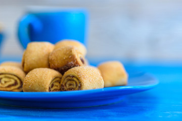 Cookies rolls with jam on a wooden turquoise background.