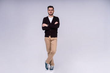 Full length portrait of a smiling casual man standing isolated on a gray background.