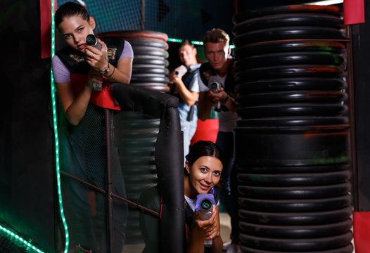 Friends playing laser tag  game with laser guns together in dark labyrinth