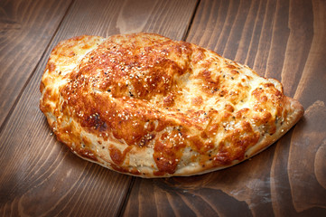 Italian pirogue pizza on wooden table with melting baked cheese