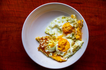 Healthy organic egg breakfast in a white bowl dish on a dark wood table  