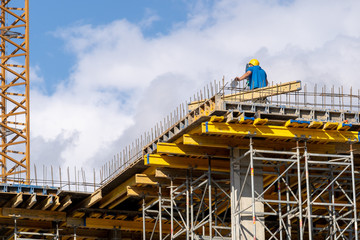 Man in protect safe helmet on high rise building with survey