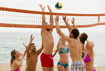 adults throwing ball over net and laughing