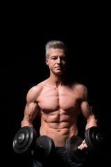 Fototapeta na wymiar Closeup of a muscular young man lifting weights on dark background