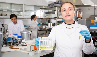 Female chemist analyzing liquid in test flasks