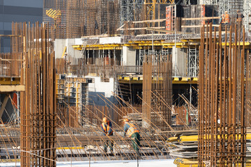 Two adult workman bind reinforcement on incomplete building