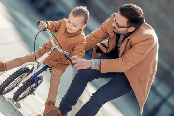 Father help his son to ride a bicycle