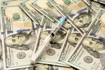close up of syringe with injection on dollar banknotes
