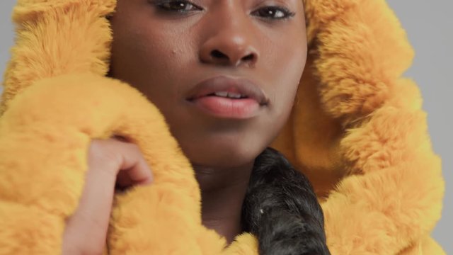 mixed race black woman wrapping up in yellw fur hood