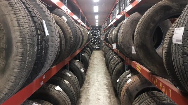 Used truck and car tires for sale in corridor with various shapes and sizes to choose from; panned upwards. 