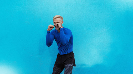 Young attractive man boxing on blue background © Vasya