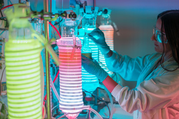 Female scientist working in a biotechnology laboratory with reactors and microalgae cultivation