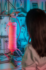 Female scientist working in a biotechnology laboratory with reactors and microalgae cultivation