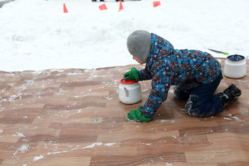 Boy playing curling with kettles