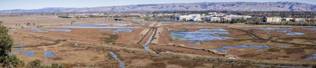 Aerial view of marshland in Don Edwards Wildlife Refuge, office buildings in the background; San...