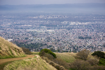 Aerial view of residential areas of San Jose, California on a rainy day; hiking trail in Sierra Vista park on the right; the city's financial district in the background;