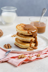 Pancakes with boiled condensed milk and walnuts on plate with fork