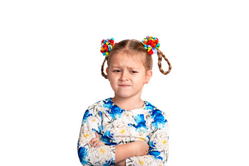 Studio waist up portrait of a little girl wearing shirt with a print and with two pigtails and color bows on a white background.stands with arms crossed endures about what or is upset