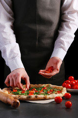chef making pizza lays out cherry tomatoes in vegetarian pizza