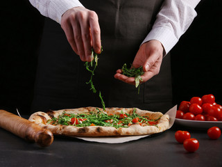 chef sprinkles arugula in pizza