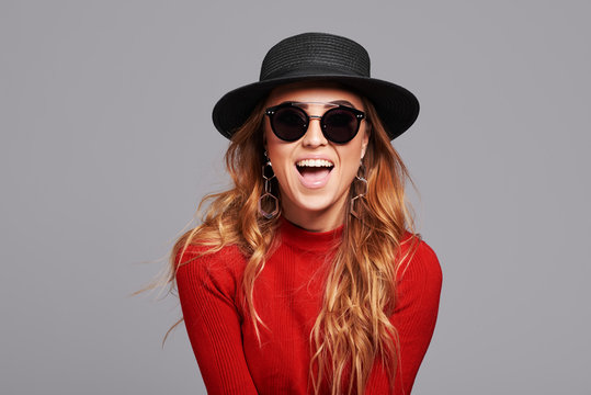 Fashion portrait pretty woman in black rock style hat and sunglasses over grey background. Holiday concept