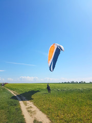 Adult paraglider wants to start near cliff along baltic sea coastline and green meadow wheat field...
