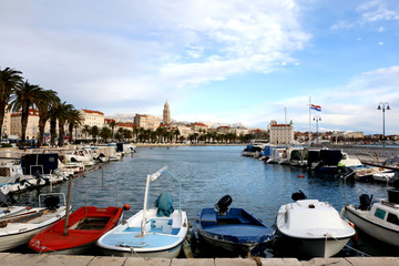 Fototapeta na wymiar Small old boats in port of Split, Croatia. Riva Promenade and Saint Domnius bell tower in the background. Landmarks in Split. 