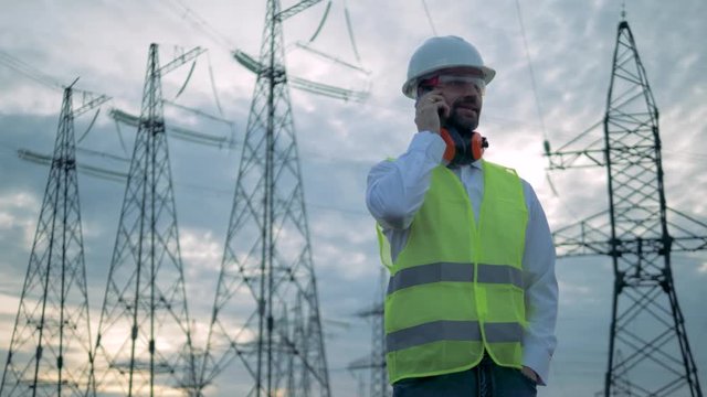 Phonecall of male technician while standing beside electrical transmission lines