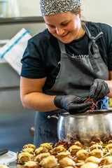 Female Chef Putting Ingredients of Burgers on a Sliced Bread Spread on a Table in Black Gloves - Concept of the Hard Working Person and the Hygiene in the Kitchen