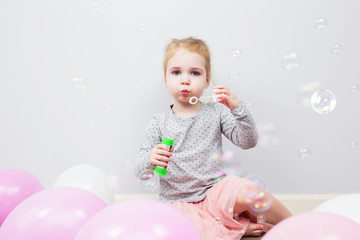 Beautiful little blonde girl, has happy fun cheerful smiling face, pink dress, soap bubble blower....