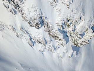 Aerial view of snow covered terrain in mountain area. Mountains in central Switzerland. Alps with snow in beautiful light with shadow and sun.