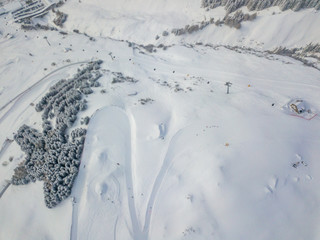 Aerial view of snow covered road with curve used as ski slope for downhill skiing in Switzerland.