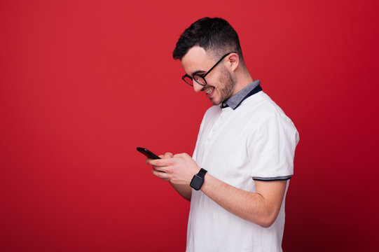 A young boy model is usig his  mobile over red background