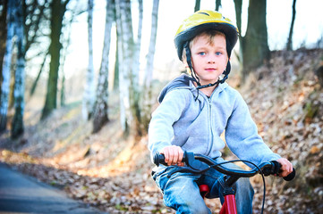 Obraz premium Boy riding his bike on a spring country track. Road concept for safety and child development