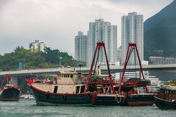 Hong Kong, China  - May 12, 2010: Black and red fishing vessels docked in  harbor with white tall...