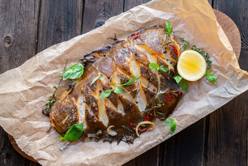 baked flounder fish whole with seasonings, lemon and Basil on parchment, top view