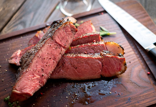 Medium Rare Ribyey Steak Cut Into Pieces On Board