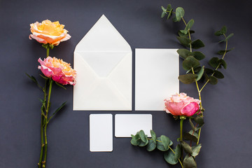 A wedding mock up composition. Wedding Invitation, envelope, paper cards with peony rose flower and sprig of eucalyptus on grey background . Top view, flat lay, copy space